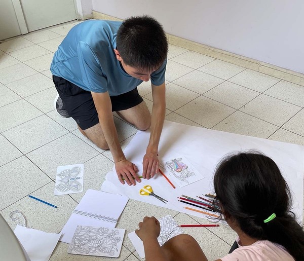 College student coloring with young girl.