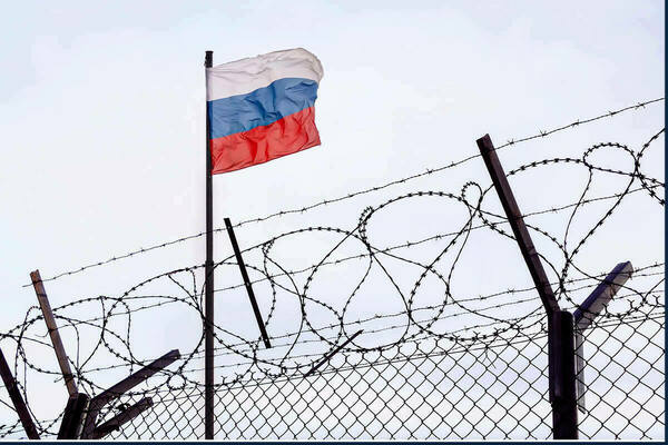Barbed wire in front of a Russian flag.