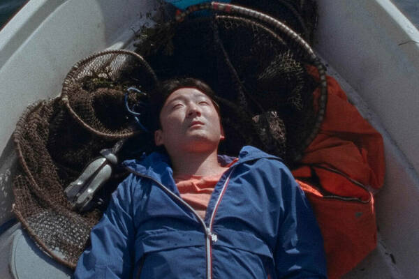 Young man lying in a boat looking off-camera.