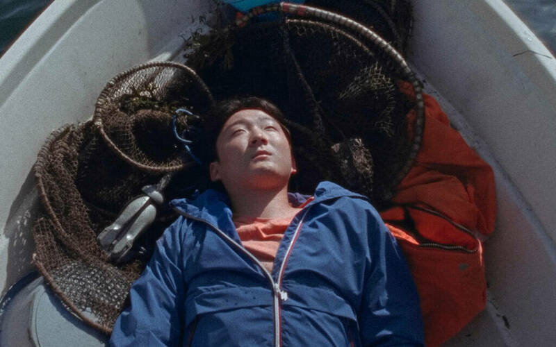 Young man lying in a boat looking off-camera.