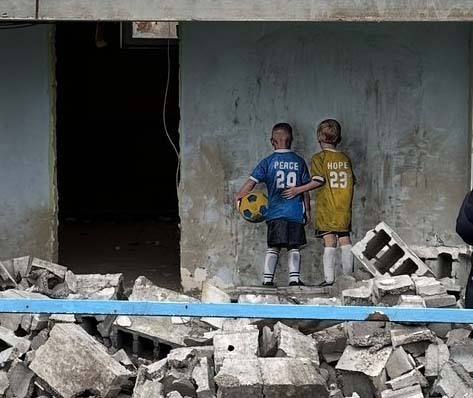 Mural with two boys in Ukrainian color jerseys labeled Peace and Hope. Their backs are to the viewer and they are holding a soccer ball.