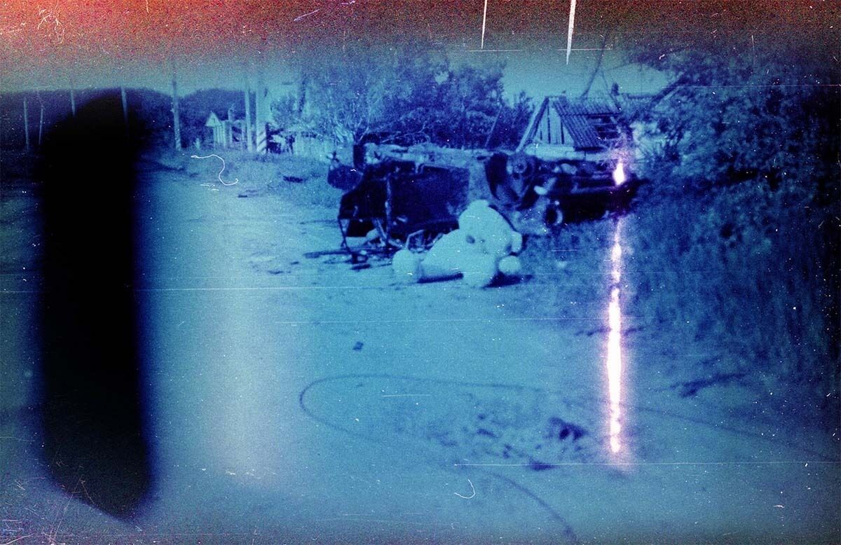 Photograph on expired film depicting destruction on the side of a road.