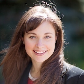 Outdoors headshot of Kristina Hook, who is wearing a navy blazer over a red top.