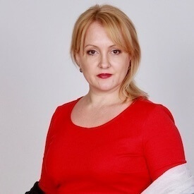 Headshot of Natalia Slobodian against a grey backdrop. She is wearing a bright red top.