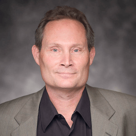 Headshot of Ian Kuijt, who is wearing a grey blazer and black shirt. He is sitting in front of a grey backdrop.