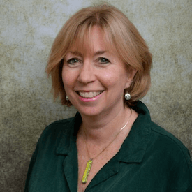 Headshot of Cathy Wanner, who is wearing a green necklace, green blouse, and silver circular earrings.