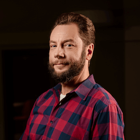 Headshot of Alejandro Danylyszyn, who is wearing a blue and red plaid shirt.