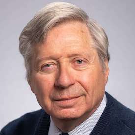 Headshot of Dr. George Liber, who is wearing a navy blazer over a blue shirt and navy tie.